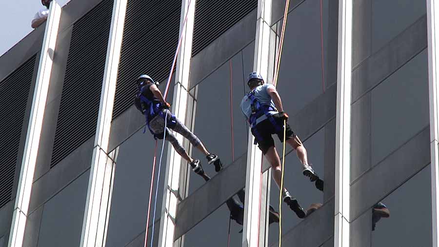 Two people rappelling down the side of a building in downtown Raleigh, North Carolina.